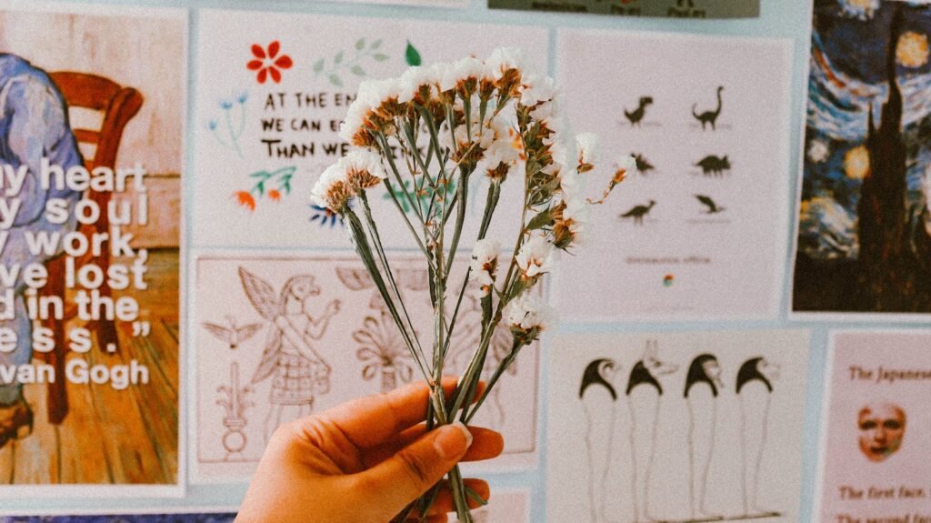 A hand holding white flowers against a creative wall collage in Ankara. Vibrant and artistic.